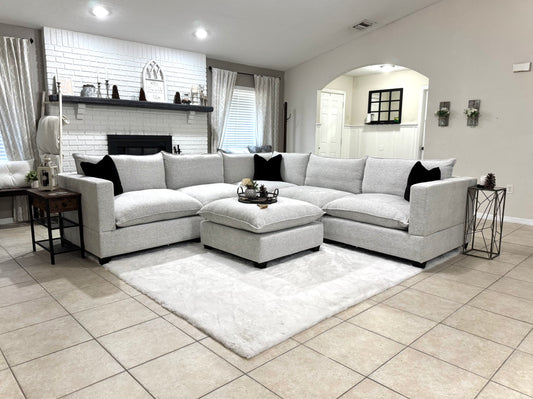 Modern living room with a sectional sofa, ottoman, and decorative items.