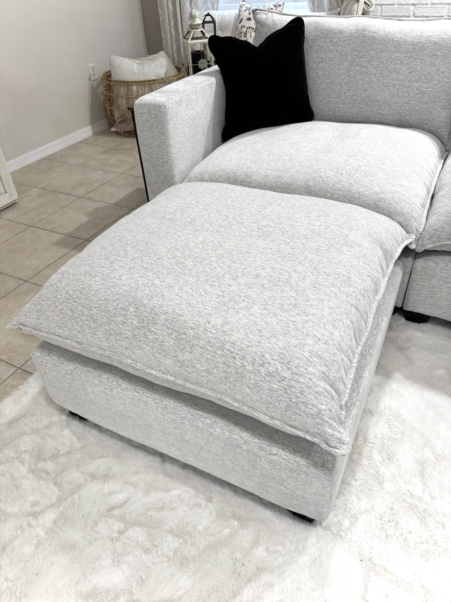 Chaise lounge with a black pillow on a light-colored rug in a room.