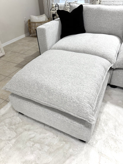 Chaise lounge with a black pillow on a light-colored rug in a room.