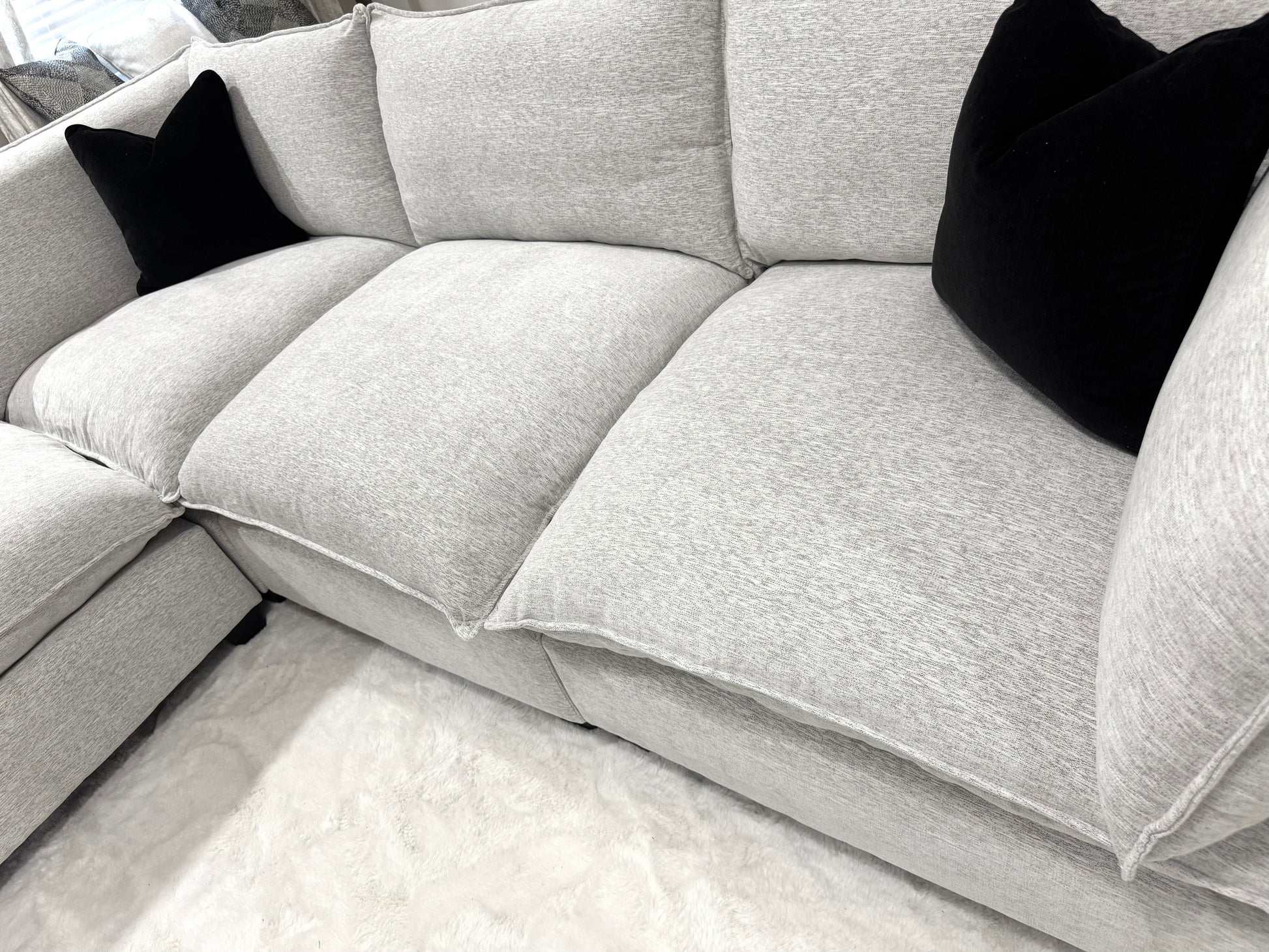 Sectional sofa with black pillows on a light-colored floor.