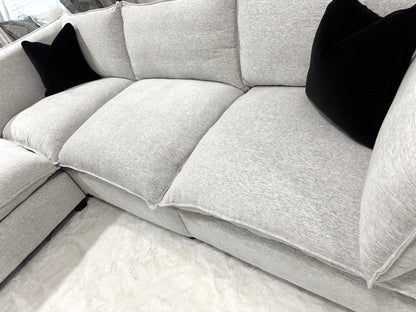 Sectional sofa with black pillows on a light-colored floor.