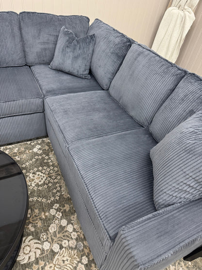 Sectional sofa with textured cushions on a patterned rug.