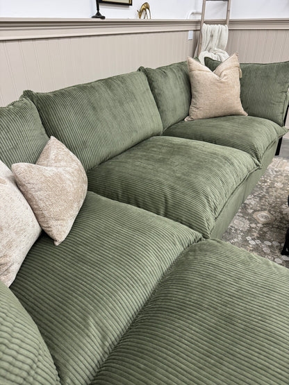 Green sofa with beige pillows in a room setting